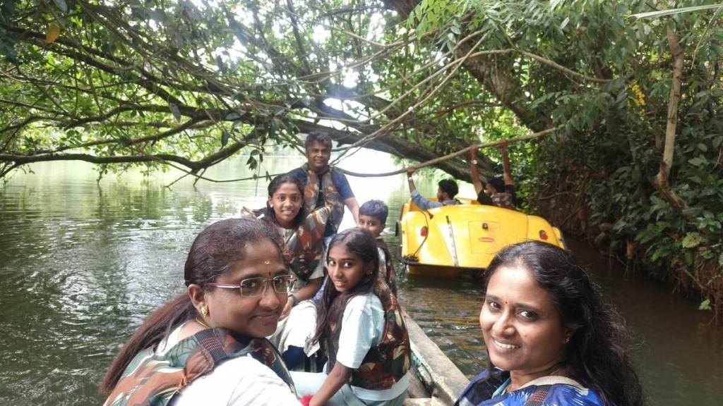Both families enjoying a boat ride surrounded by greenery at Thirparappu